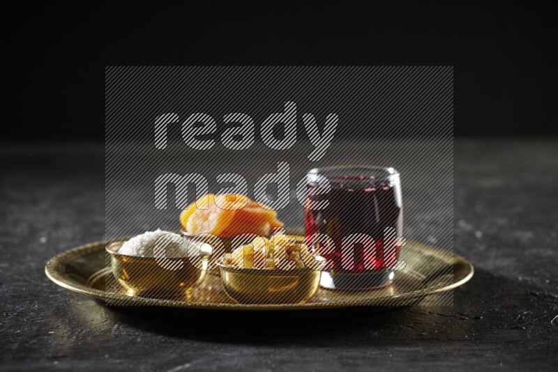 Dried fruits in metal bowls with Hibiscus on a tray in dark setup