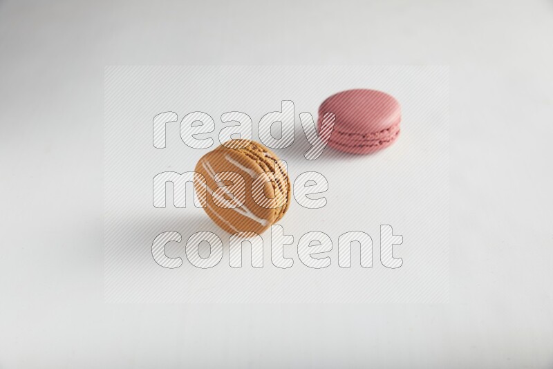 45º Shot of of two assorted Brown Irish Cream, and Pink Raspberry macarons on white background