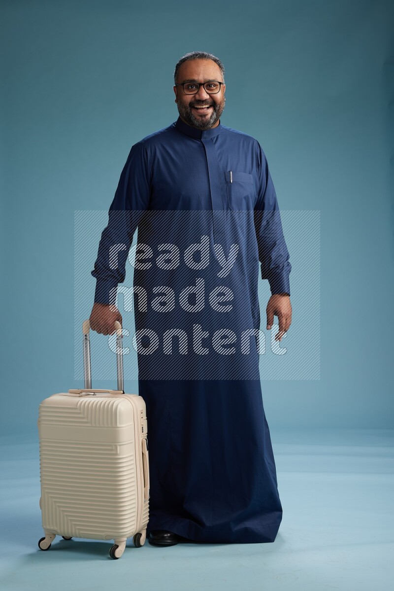 Saudi Man without shimag Standing pulling travel bag on blue background