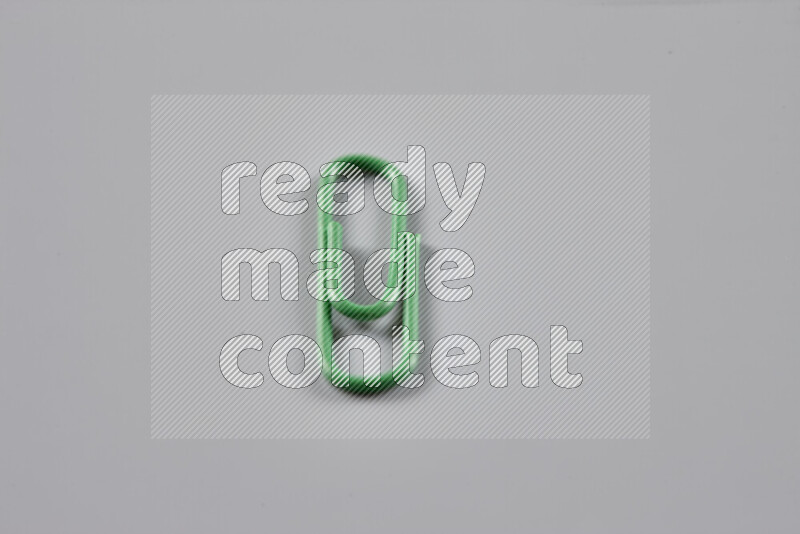 Green paper clips isolated on a grey background