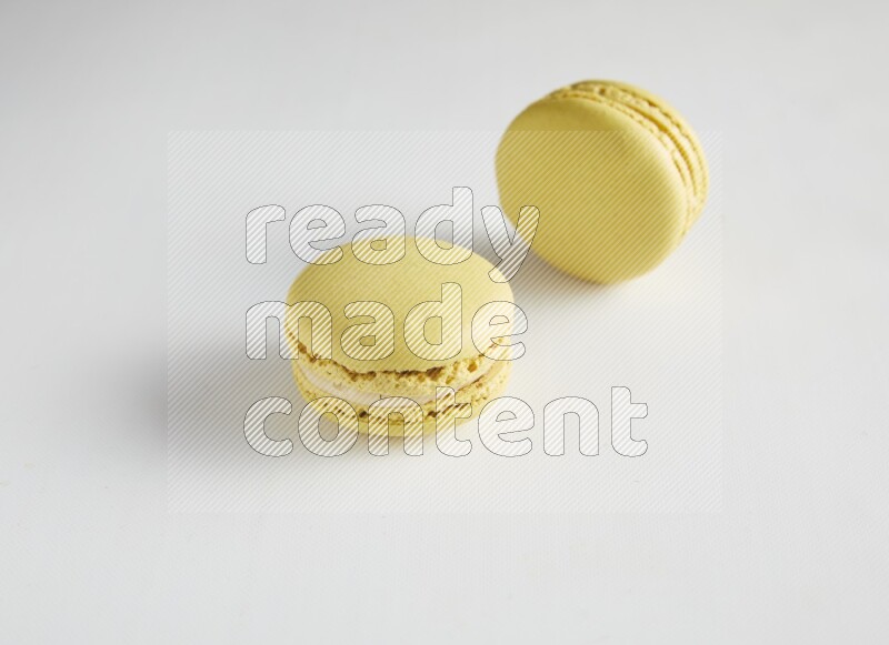 45º Shot of two Yellow Lime macarons on white background