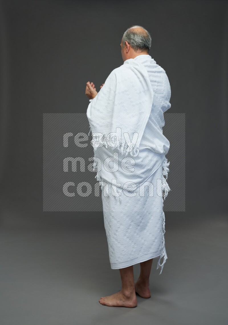 A man wearing Ehram Standing dua'a on gray background