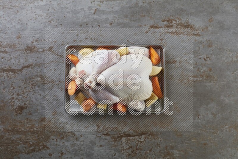 whole Raw chicken on a small oven trey direct on a rustic grey background
