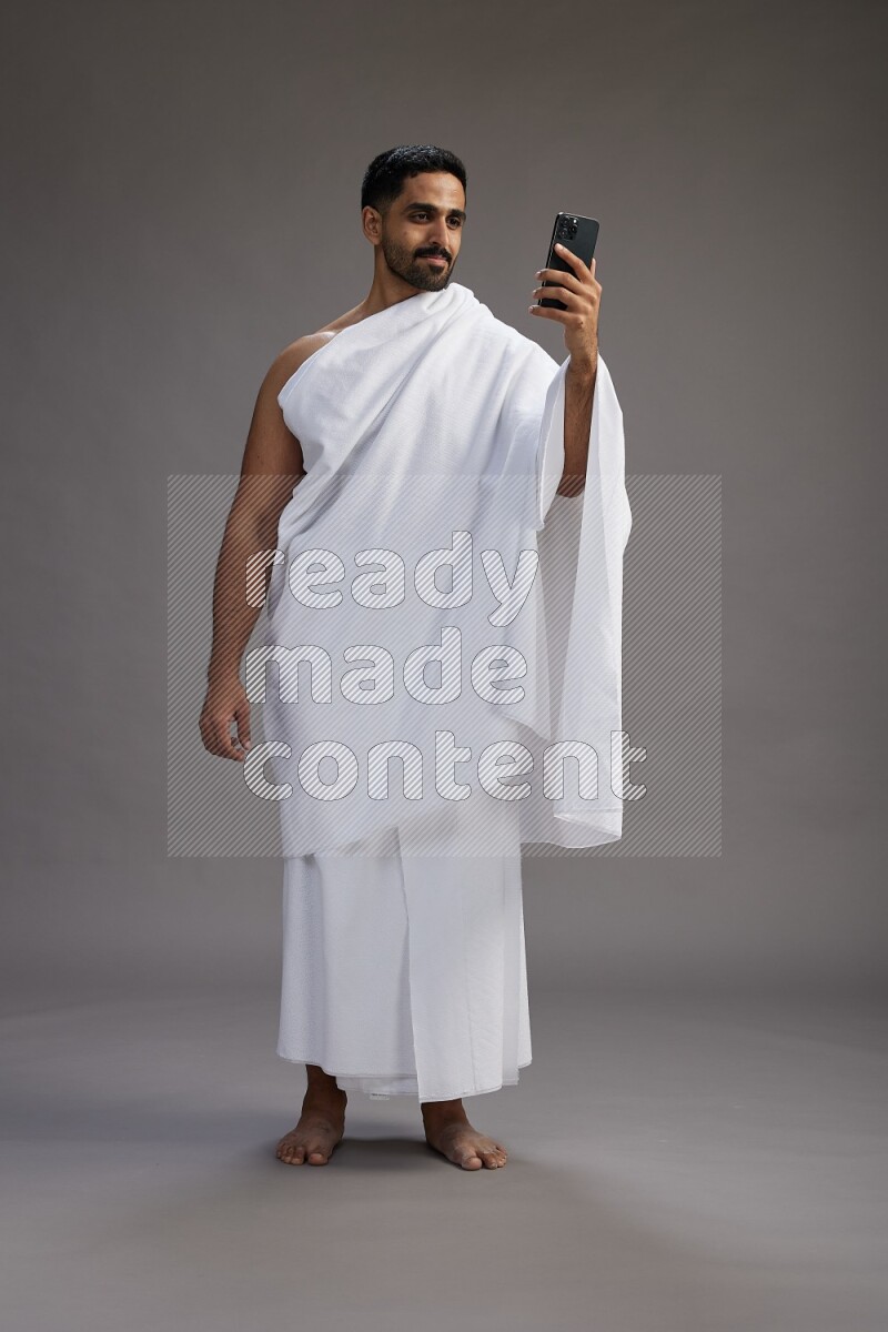 A man wearing Ehram Standing taking selfie on gray background