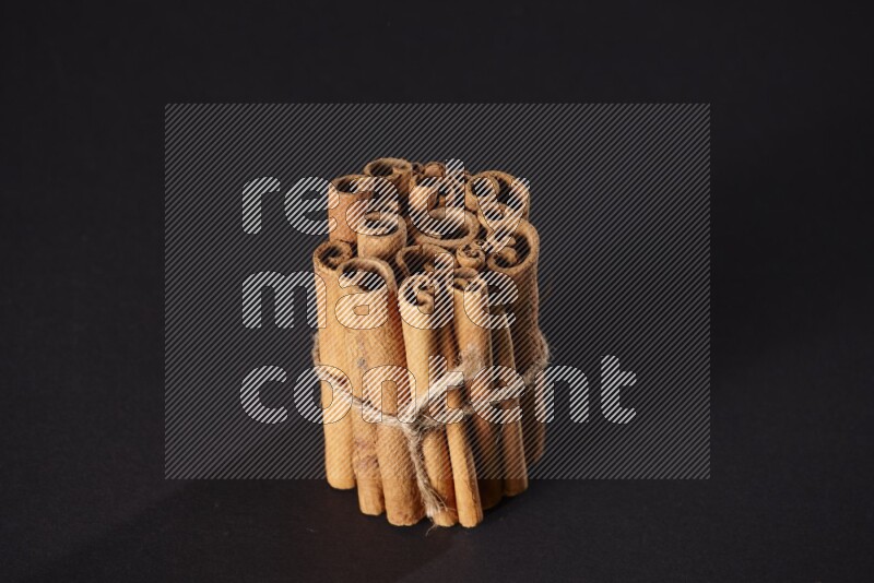 A bounded stack of cinnamon sticks on black background