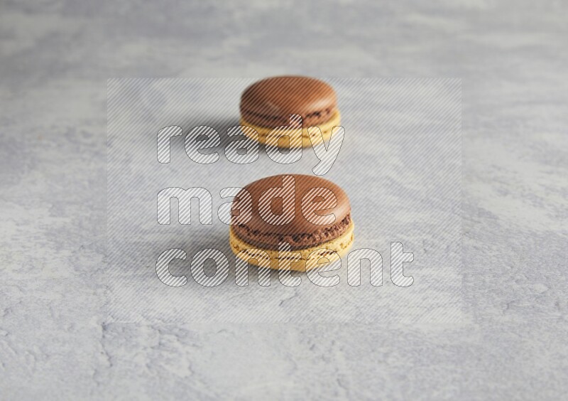 45º Shot of two Yellow and Brown Chai Latte macarons r on white  marble background