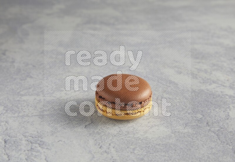 45º Shot of Yellow and Brown Chai Latte macaron on white  marble background
