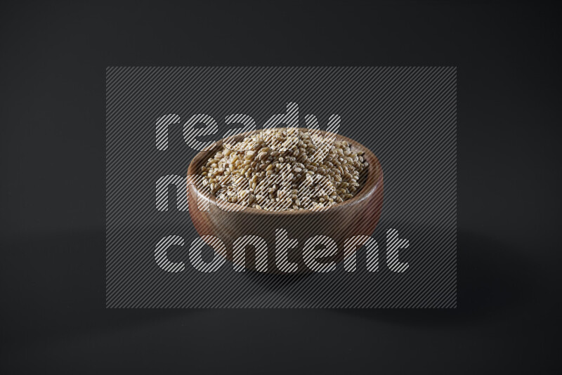 Hulled wheat in a wooden bowl on grey background
