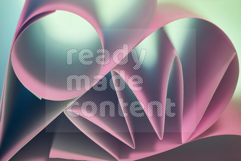An artistic display of paper folds creating a harmonious blend of geometric shapes, highlighted by soft lighting in green and pink tones