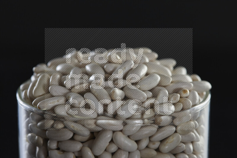 White beans in a glass jar on black background