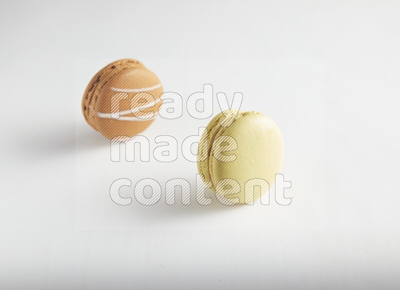 45º Shot of of two assorted Brown Irish Cream, and Yellow Lime macarons on white background