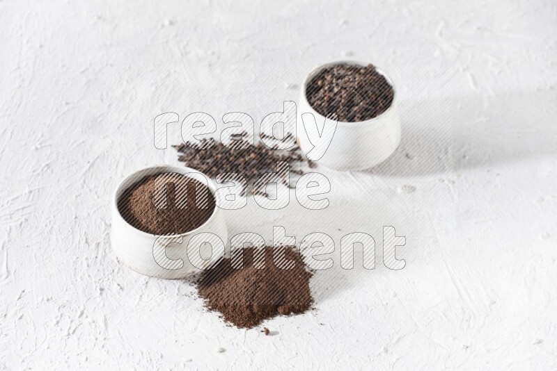 وعاءين من السيراميك بيج اللون، أحدهما مملوء بالقرنفل والآخر مملوء بالبودرة على أرضية بيضاء