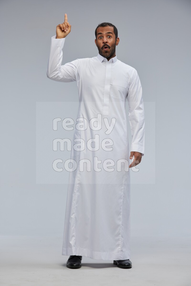 Saudi man Wearing Thob standing interacting with the camera on Gray background