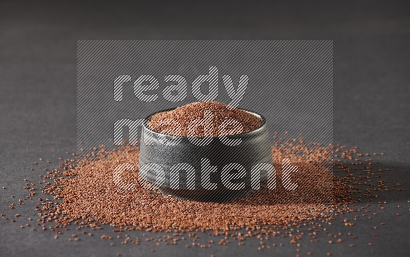 وعاء فخاري أسود ممتلئ ببذور حب الرشاد محاط بالبذور على أرضية سوداء