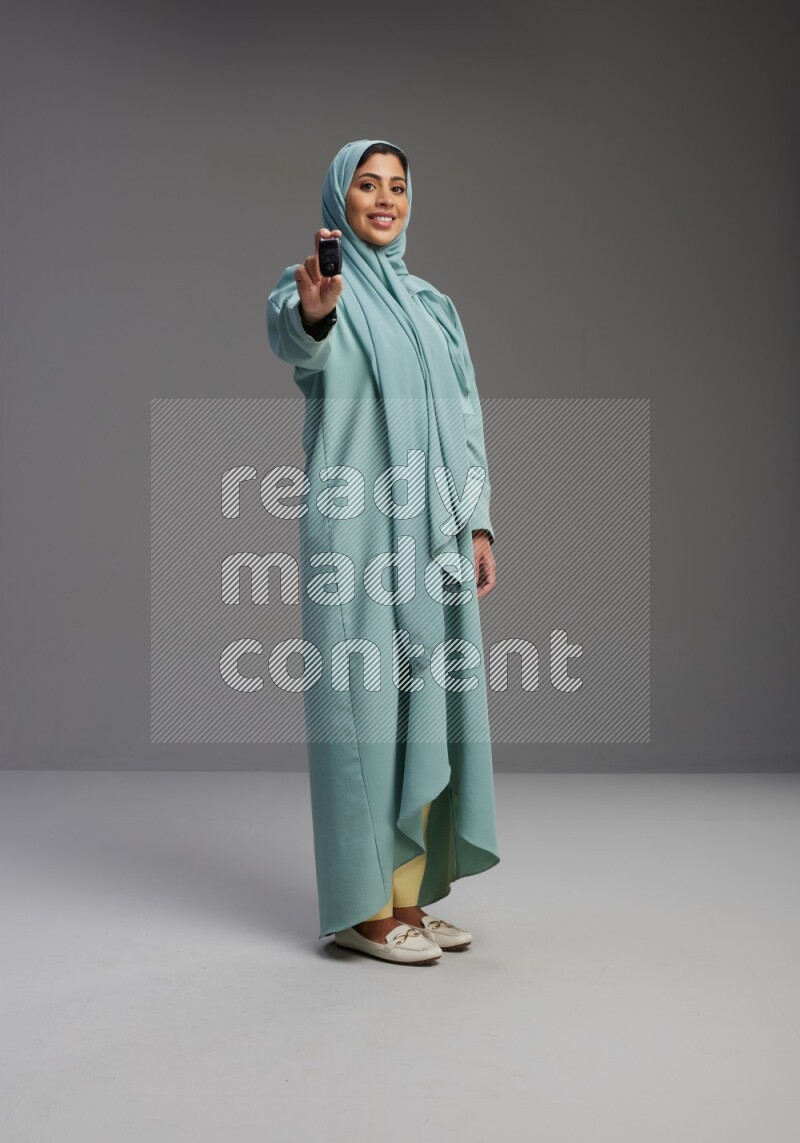 Saudi Woman wearing Abaya standing holding car key on Gray background
