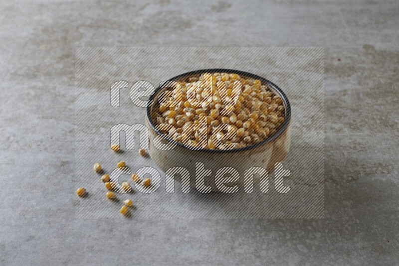 corn kernel in multi-colored pottery bowl on a grey textured countertop