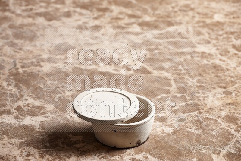 A white pottery bowl on beige marble background