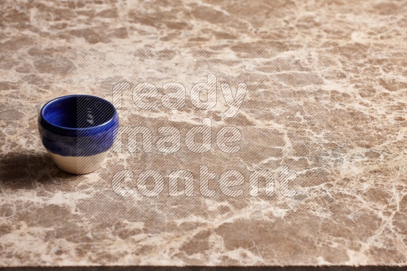 A multicolored pottery cup on beige marble background