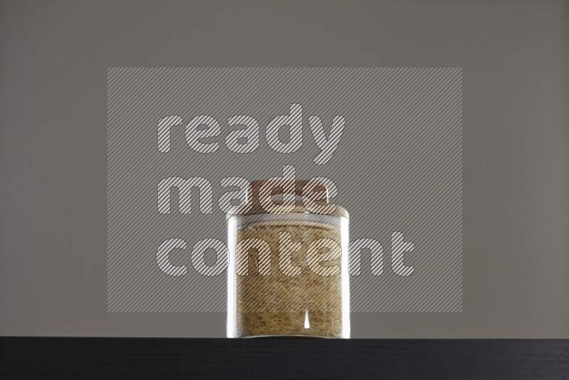 Basmati golden rice in a glass jar on black background