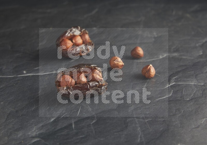 two hazelnuts stuffed madjoul dates on a black textured background