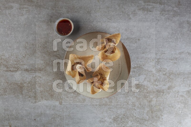 wonton cups with soy sauce ramkin on multi colored pottery on grey textured counter top
