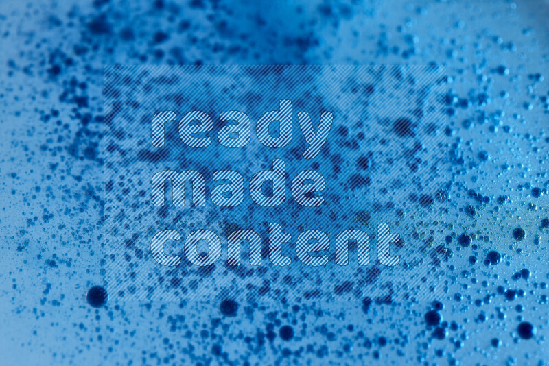 Close-ups of abstract blue watercolor drops on oil Surface on blue background