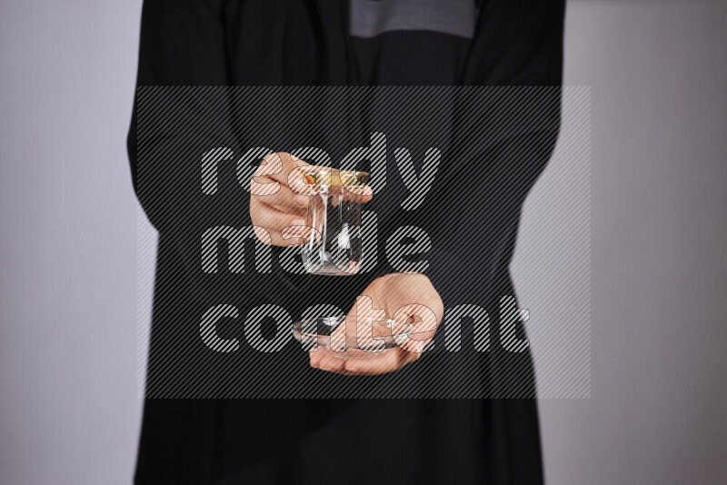 A woman in black abaya holding different glassware in different positions