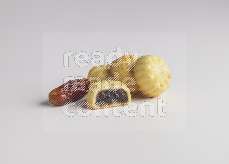 Four Pieces of Maamoul filled with date one of them is cut direct on white background