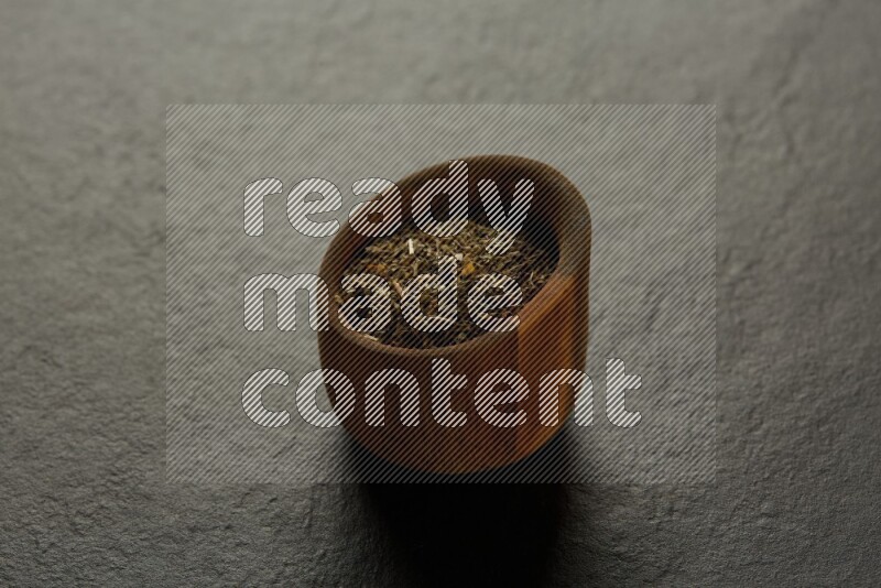 wooden round sauce bowl filled with herbs on grey textured countertop