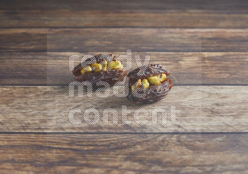 two pistachio stuffed madjoul date on a wooden background
