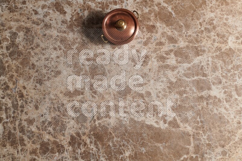 A small copper pot on beige marble background