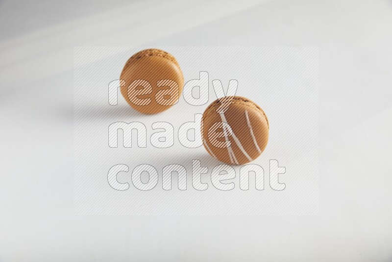 45º Shot of of two assorted Brown Irish Cream, and Brown Maple Taffy macarons  on white background