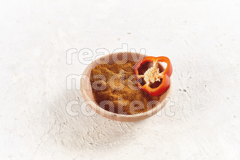 A wooden bowl full of ground paprika powder on white background