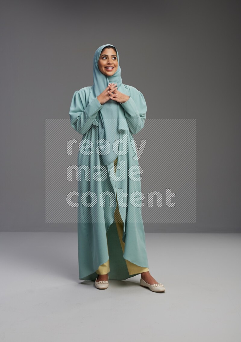 Saudi Woman wearing Abaya standing interacting with the camera on Gray background