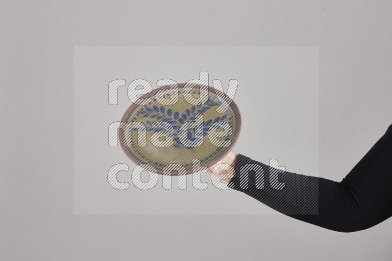 A woman in black abaya holding different pottery essentials in different positions