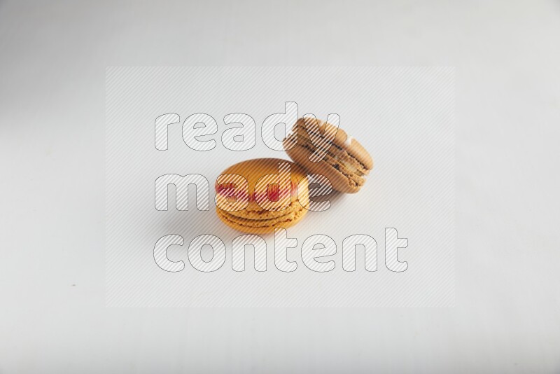 45º Shot of of two assorted Brown Irish Cream, and Orange Exotic macarons on white background
