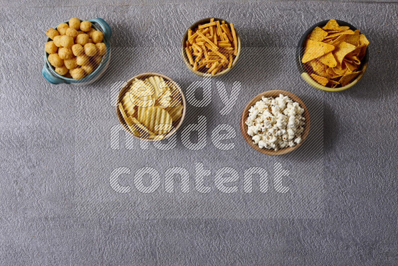 Assorted snacks in pottery bowls on grey background