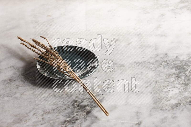 Wheat stalks on multicolored pottery plate on grey marble background