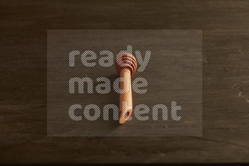 Wooden honey dipper on black slate background