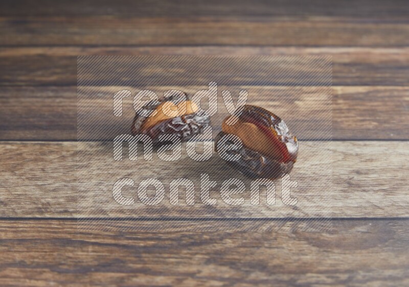 two almond stuffed madjoul dates on a wooden background