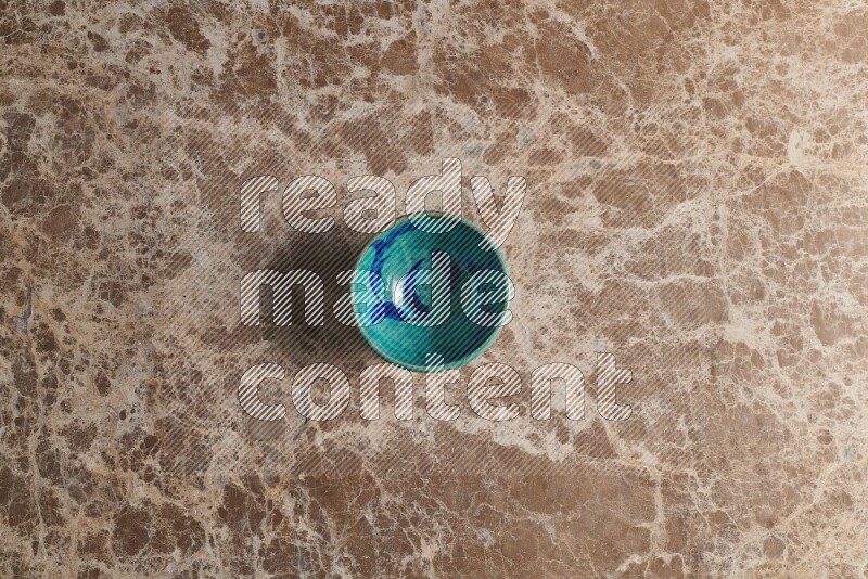 A multicolored pottery bowl on beige marble background