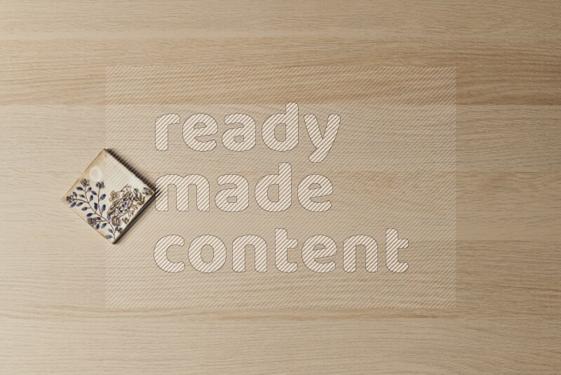 A decorative pottery coaster on light wooden background