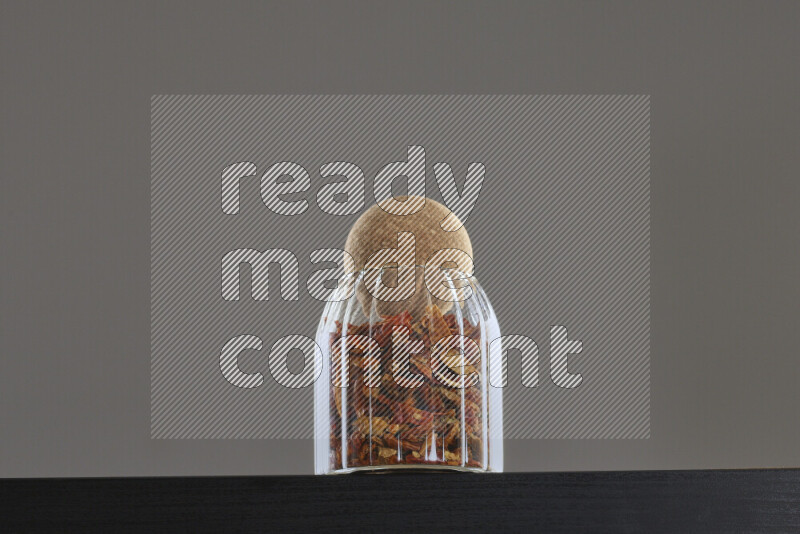 Chili pepper in a glass jar on black background