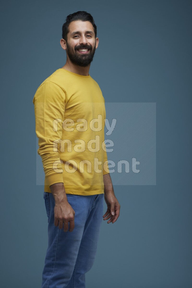 Man posing in a blue background wearing a yellow shirt