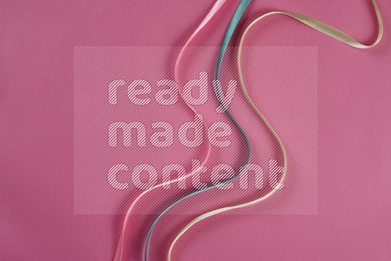 A green and pink collection of sewing and tailoring tools arranged on a pink background