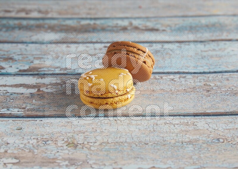 45º Shot of of two assorted Brown Irish Cream, and Yellow Piña Colada macarons on light blue background