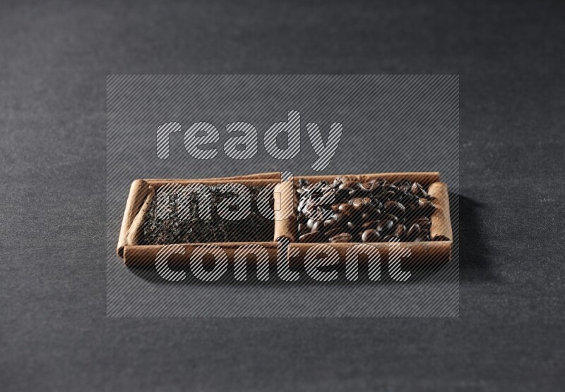 مربعان من أعواد القرفة ممتلئان بحبوب القهوة والشاي الأسود علي خلفية سوداء