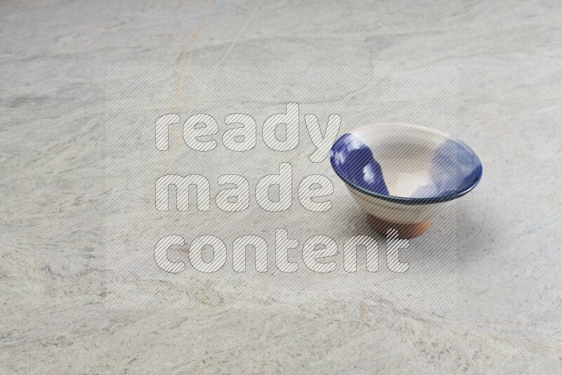 A multicolored pottery bowl on grey marble background