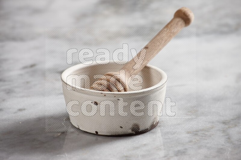 White pottery bowl with wooden honey handle in it on grey marble background
