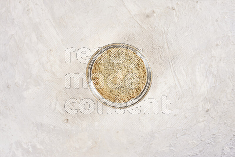 A glass bowl full of ground ginger powder on white background